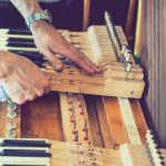 setting up an old piano. the master repairs an old piano. deep cleaning the piano. hands of professional worker repairing and tuning an old piano. toned.