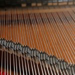 A close-up of piano strings through a raised lid