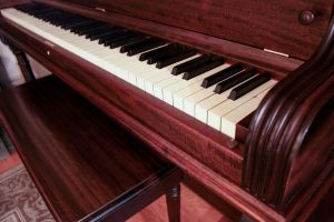 Close-up of an antique piano with reddish wood finish